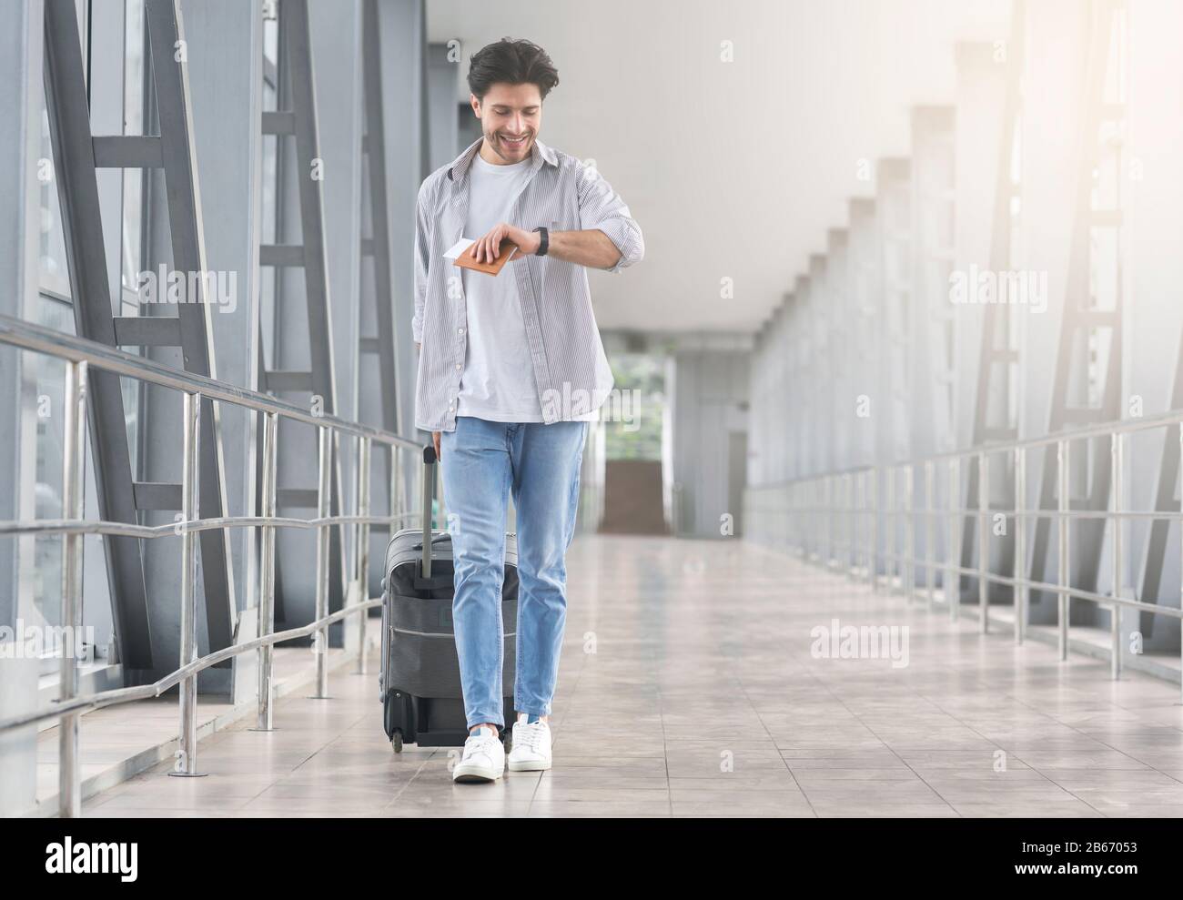 Boarding Time. Man looking at watch, walking with suitcase in airport Stock Photo