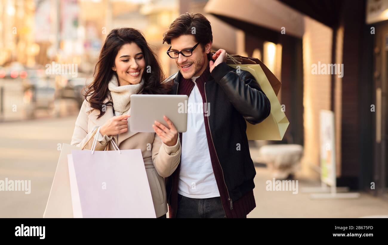 Lovely couple using tablet and walking down the streets Stock Photo