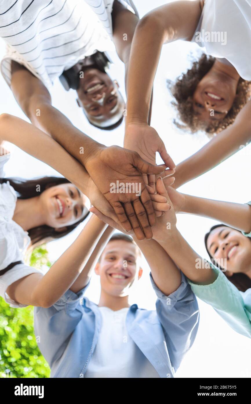 Low Angle Portrait Of Happy Teenage People Stacking Hands Together Stock Photo