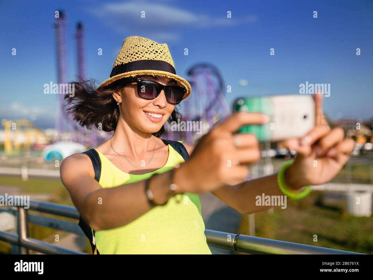 Woman using smartphone to take selfie photo in amusement park at roller  coaster background Stock Photo - Alamy