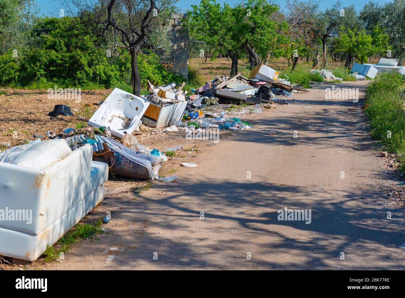 Big problem of environmental degradation. Plastic waste, non-functioning appliances and all kinds of waste left at the edge of a country road. Stock Photo
