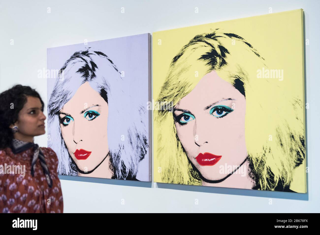 London, UK.  10 March 2020. A staff member poses next to 'Debbie Harry', 1980, by Andy Warhol. Preview of 'Andy Warhol', a retrospective of over 100 works by one of the most recognisable artists of the late 20th century.  The exhibition runs 12 March to 6 September 2020 at Tate Modern. Credit: Stephen Chung / Alamy Live News Stock Photo