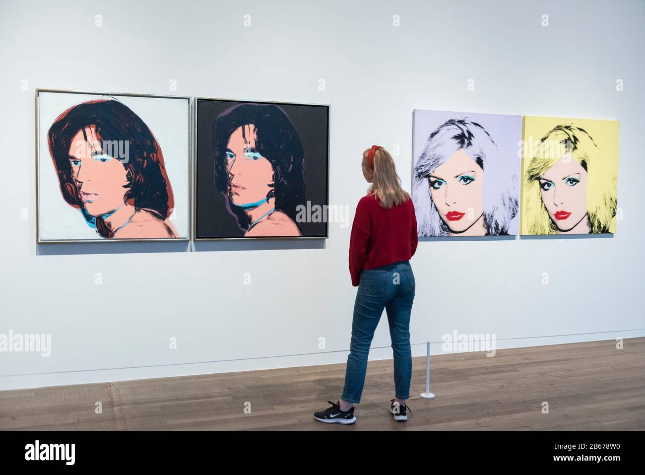 London, UK.  10 March 2020. A staff member poses next to (L to R) 'Mick Jagger' and 'Debbie Harry', 1980, both by Andy Warhol. Preview of 'Andy Warhol', a retrospective of over 100 works by one of the most recognisable artists of the late 20th century.  The exhibition runs 12 March to 6 September 2020 at Tate Modern. Credit: Stephen Chung / Alamy Live News Stock Photo