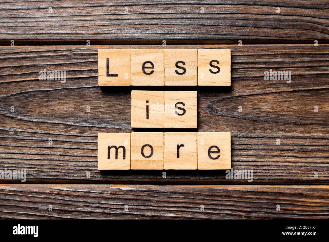 less is more word written on wood block. less is more text on table ...