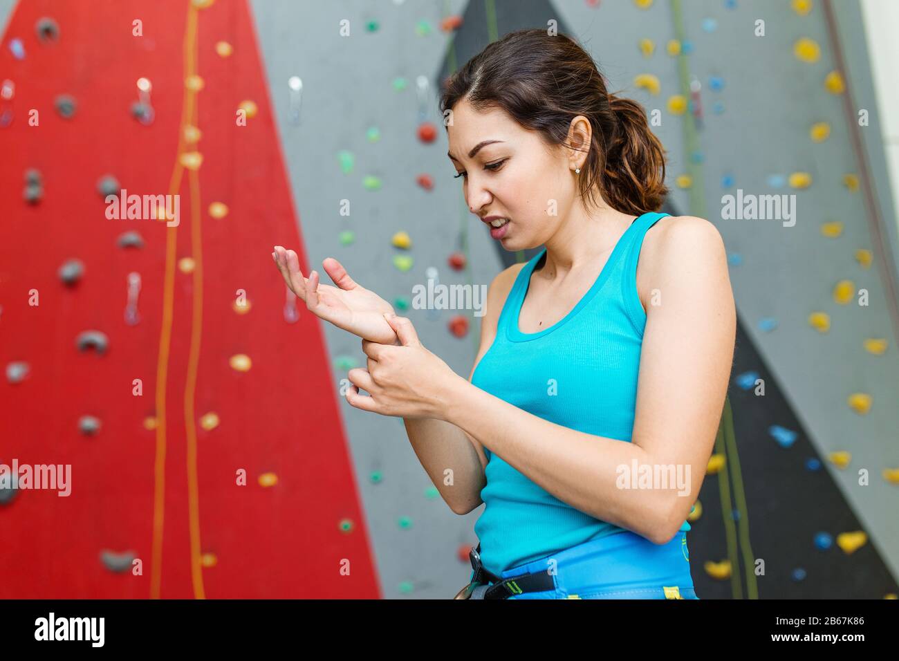 woman climber with the trauma and pain in the wrist on a background of climbing wall Stock Photo