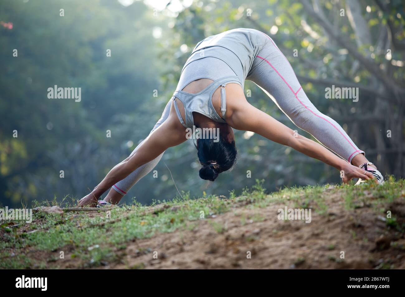 Woman in sportswear doing stretching exercise outdoors at park Stock Photo