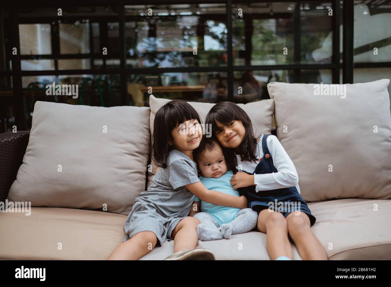 Asian children smile when sitting on the sofa hugging each other Stock ...