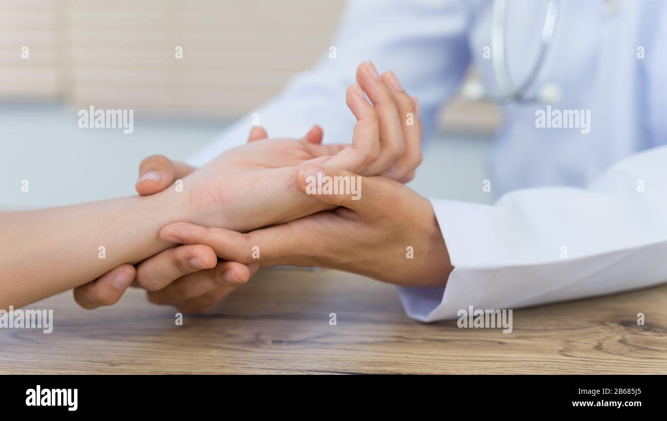 Close up of a doctor holding the patient hands doing basic medical examination and diagnostic. A doctor examines the patient in the hospital. Stock Photo