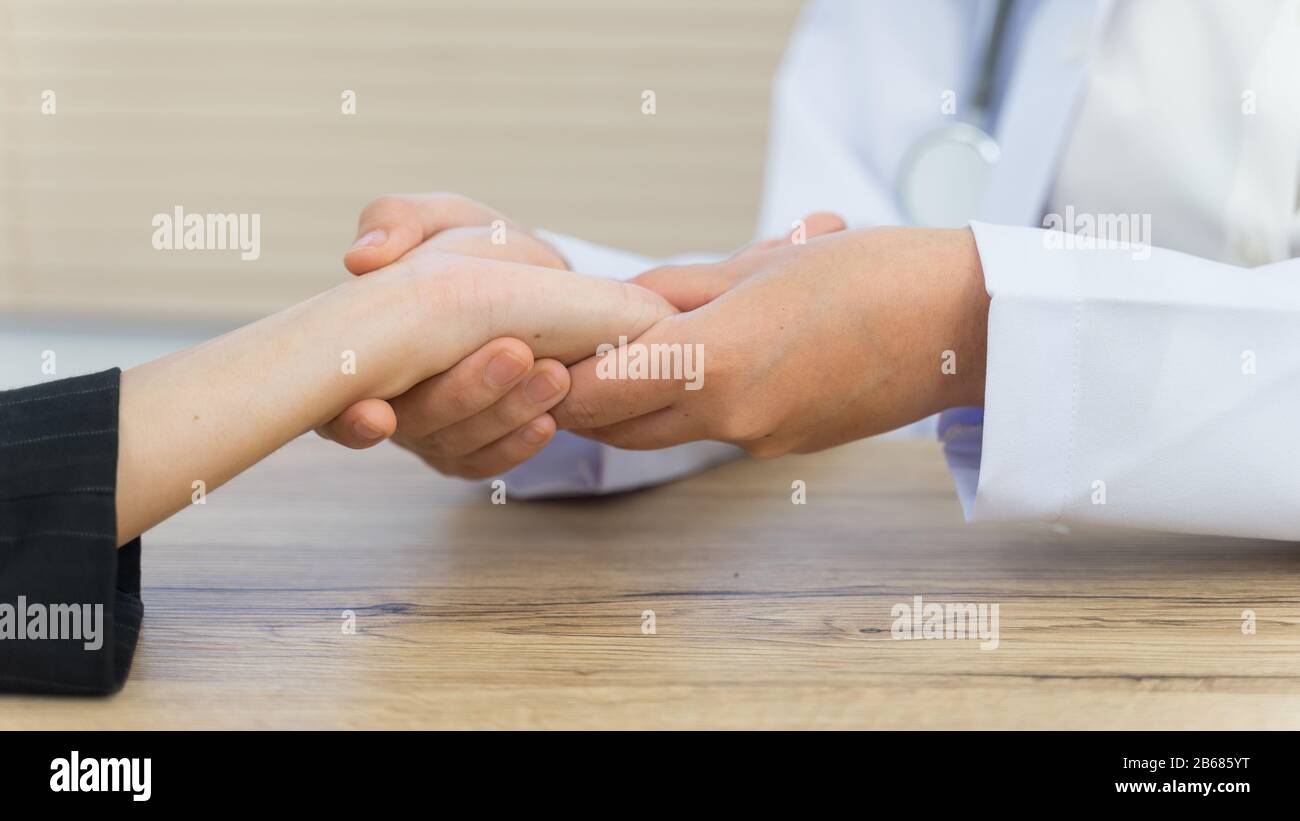 Close up of a doctor holding the patient hands doing basic medical examination and diagnostic. A doctor examines the patient in the hospital. Stock Photo