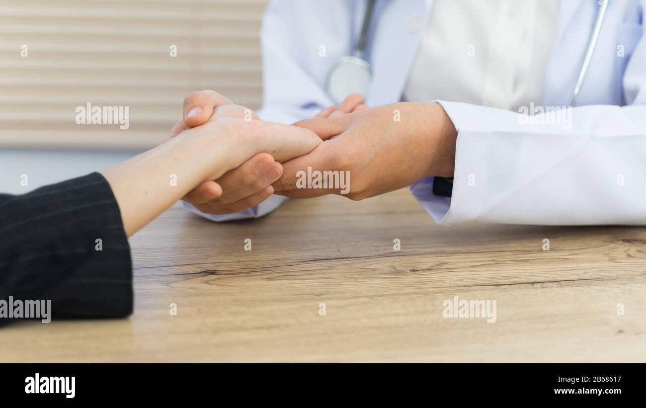 Close up of a doctor holding the patient hands doing basic medical examination and diagnostic. A doctor examines the patient in the hospital. Stock Photo