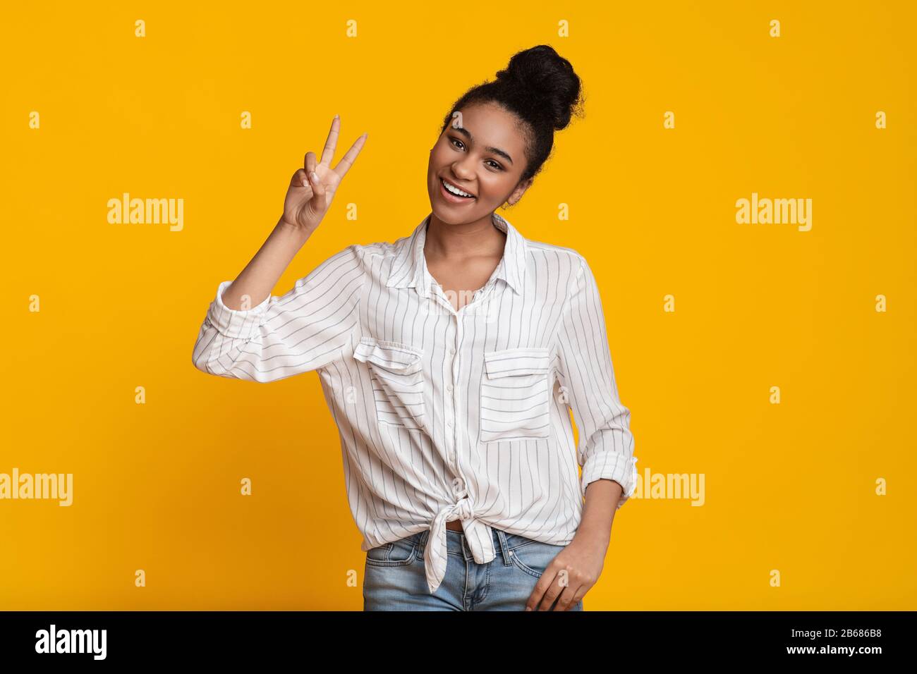 Happy Black Woman Showing Peace Gesture, Gesturing V-Sign Over Yellow Background Stock Photo