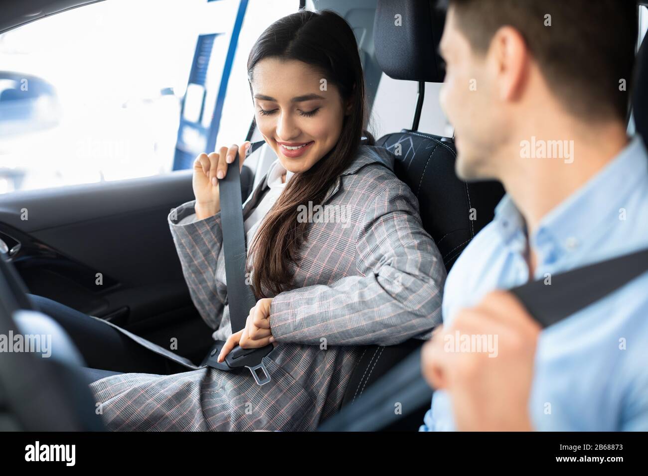 Couple In Car Putting On Seat Belts In Dealership Showroom Stock Photo