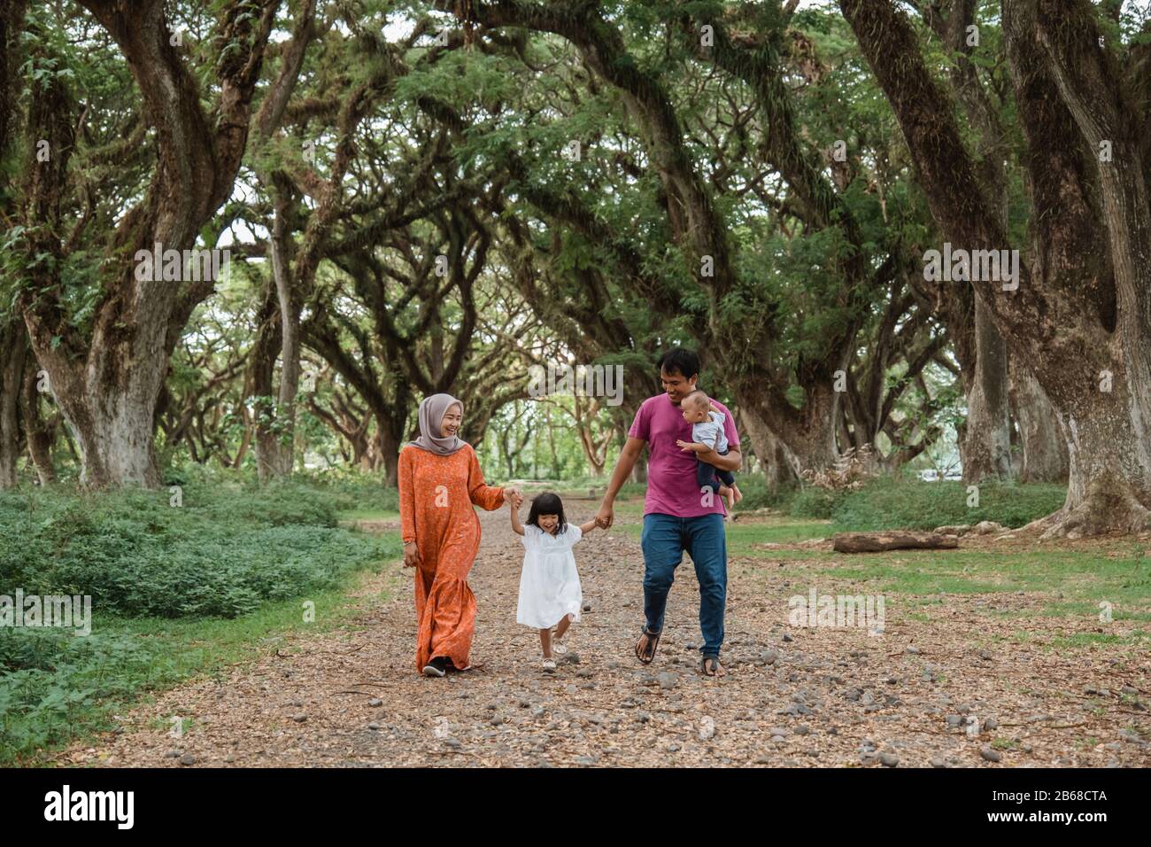 Muslim families enjoy holidays together, father, mother and two children walking in the park Stock Photo
