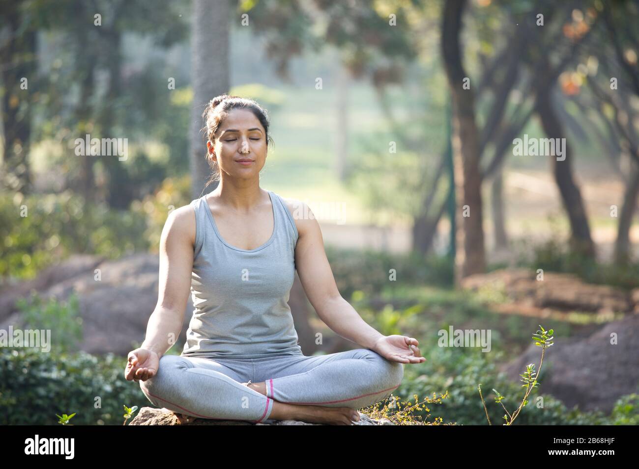 Woman practicing yoga in lotus position at park Stock Photo