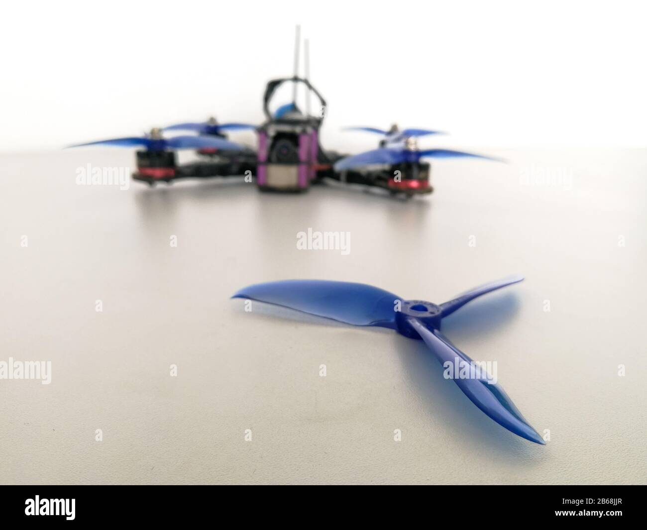 Plastic blue drone propeller in front of racing quadcopter Stock Photo