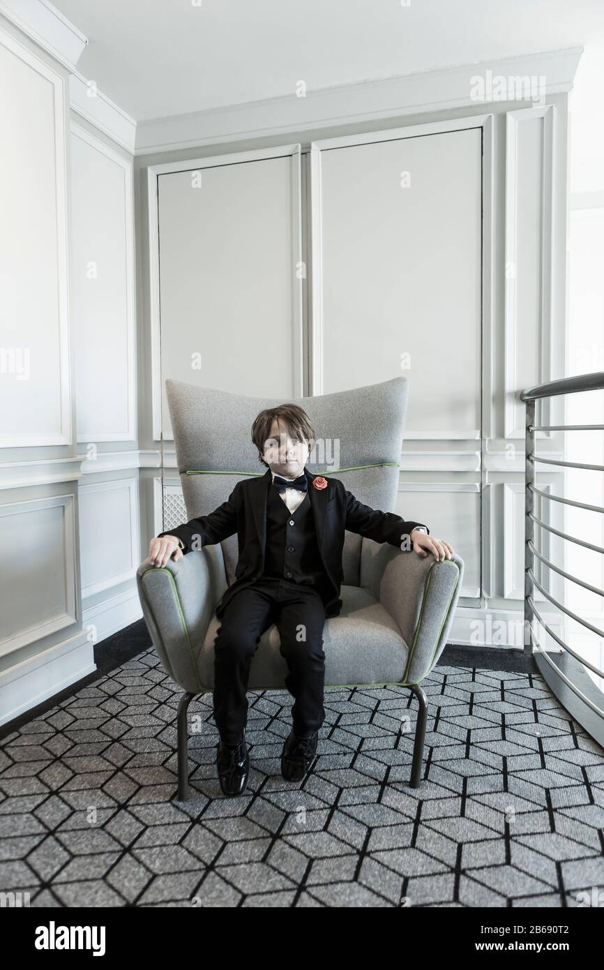 portrait of 6 year old boy sitting in chair Stock Photo