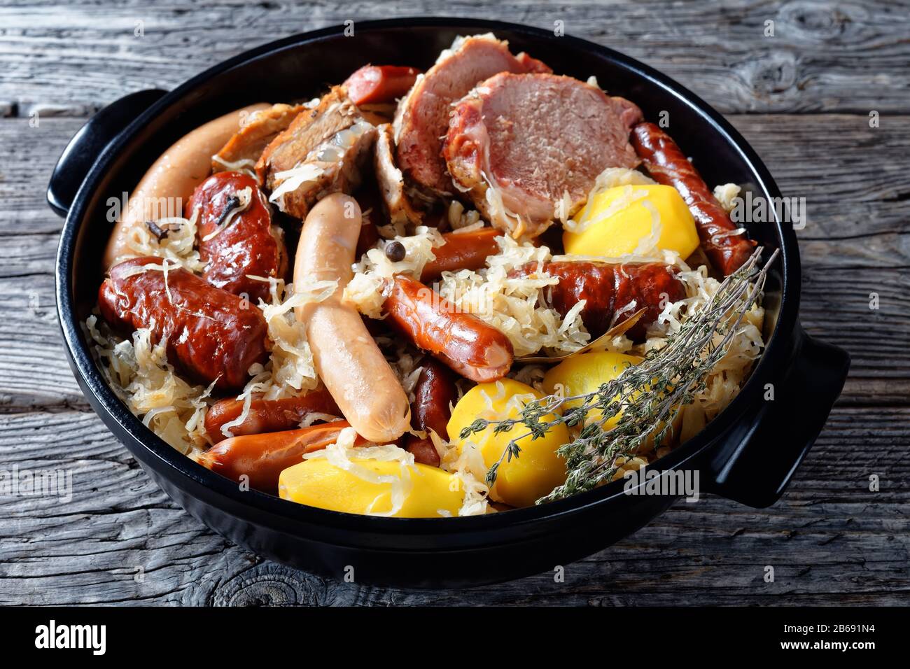 Alsace dish: sour cabbage stew with meat: pork loin and bacon and sausages and potato cooked in white wine thyme, juniper berries, garlic served on a Stock Photo