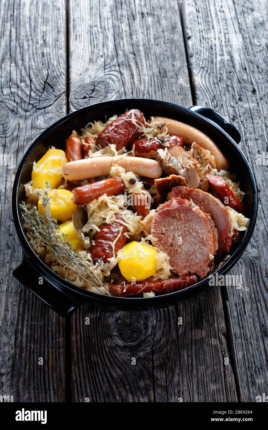 Old fashioned french Alsace dish choucroute garnie sour cabbage stew with pork loin, bacon, and sausages cooked with potato in white wine, thyme, clov Stock Photo