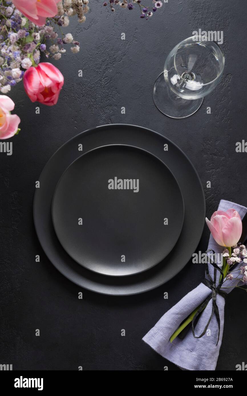 Elegance table setting spring pink tulips on black. Easter dinner. Top view. Stock Photo