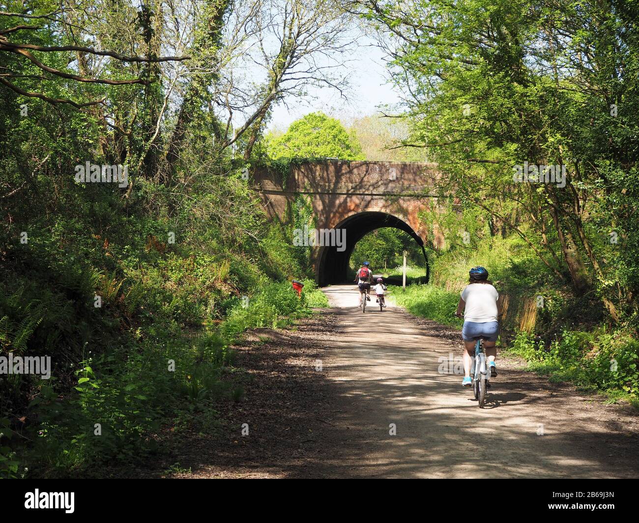 family cyclists riding along an old railway on a cycle path  Stock Photo
