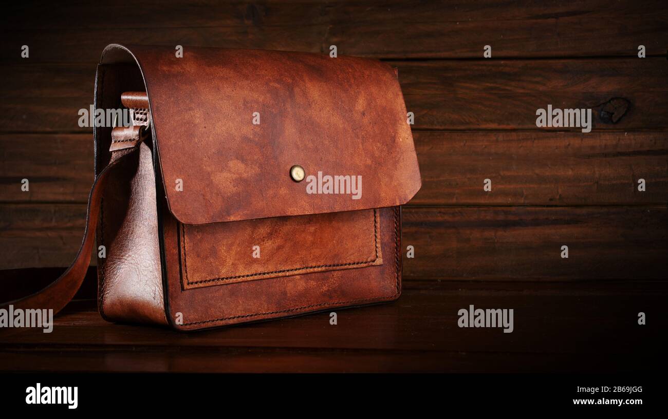 Leather messenger shoulder bag on wooden background Stock Photo