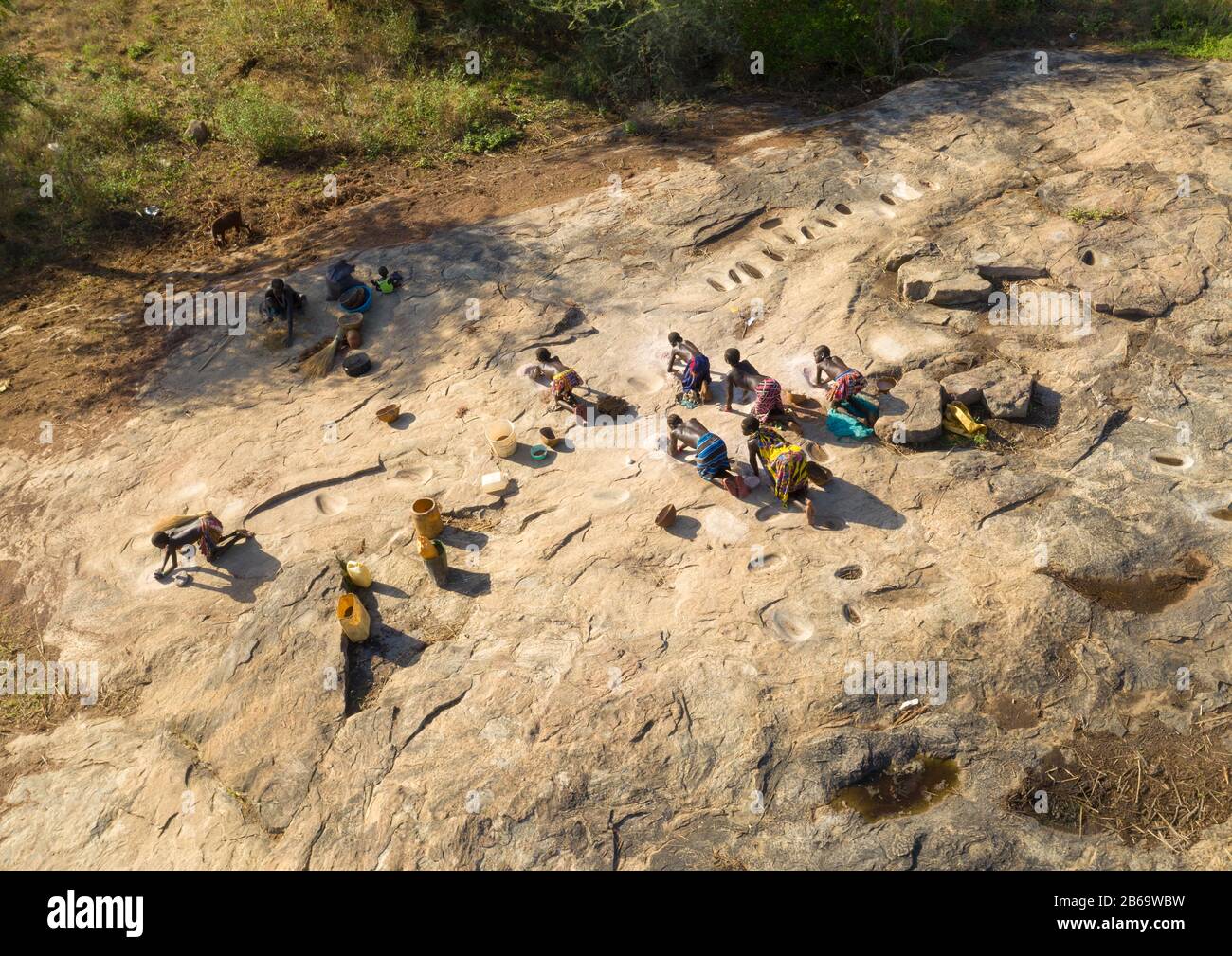 Larim tribe women grinding grains in holes in a rock, Boya