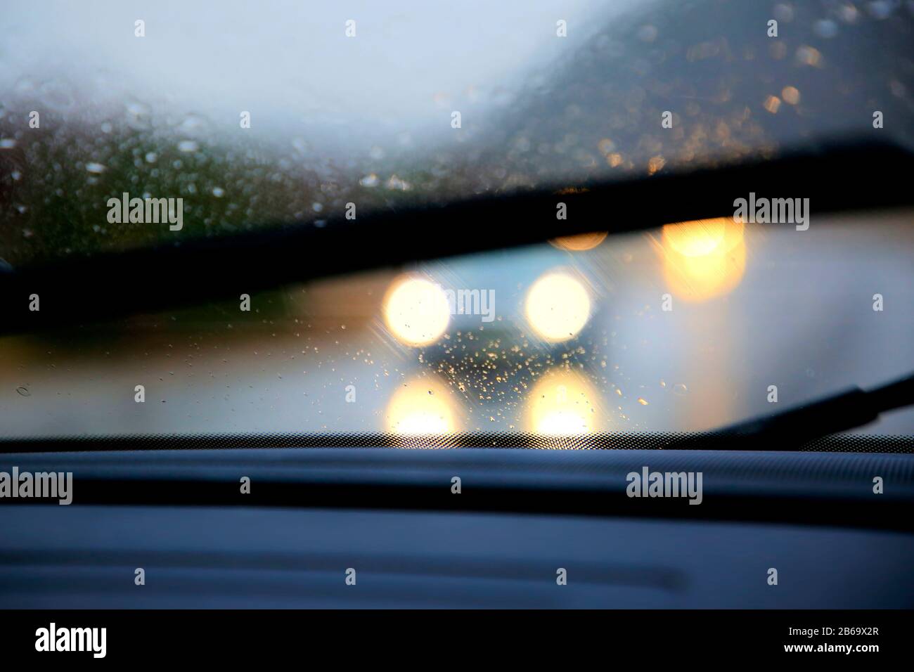 Driving on highway in heavy rain,  windshield wipers on, low visibility with dazzling headlights of oncoming traffic. Stock Photo