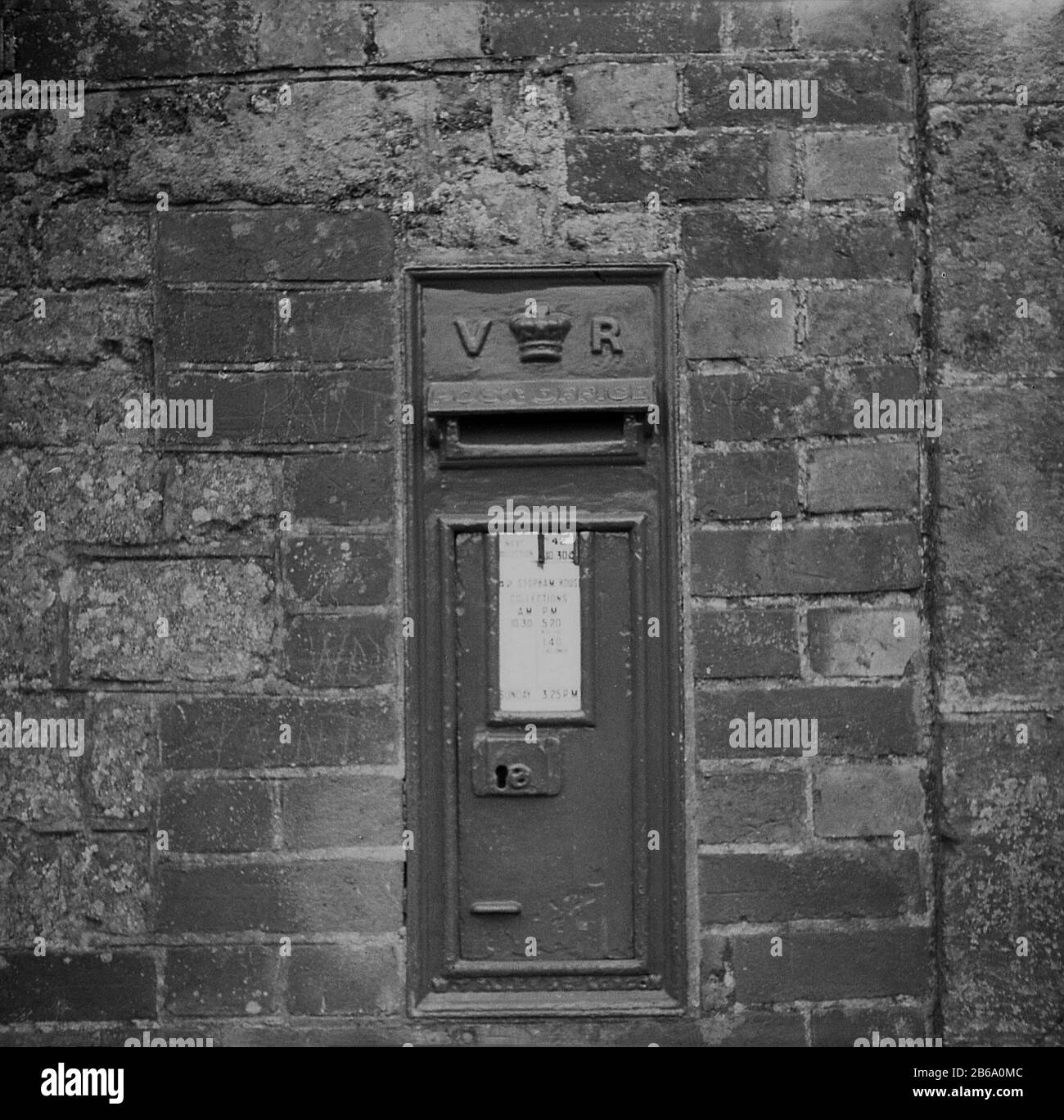 1950s, historical, a Royal Mail victorian letterbox built into brick wall, Stopham House, Pulborough, West Sussex, England, UK, recently painted. This old letterbox with the initials VR on, was constructed between 1853-1901 in the reign of British Queen Victoria. Postboxes were first introduced in Britain in 1853. Stock Photo