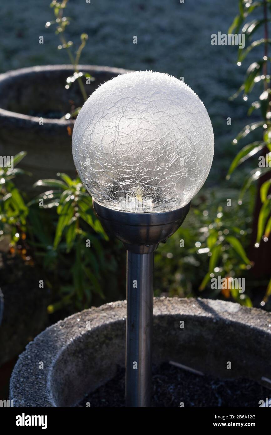 A naturally frosted plastic globe solar light in the garden in winter Stock Photo