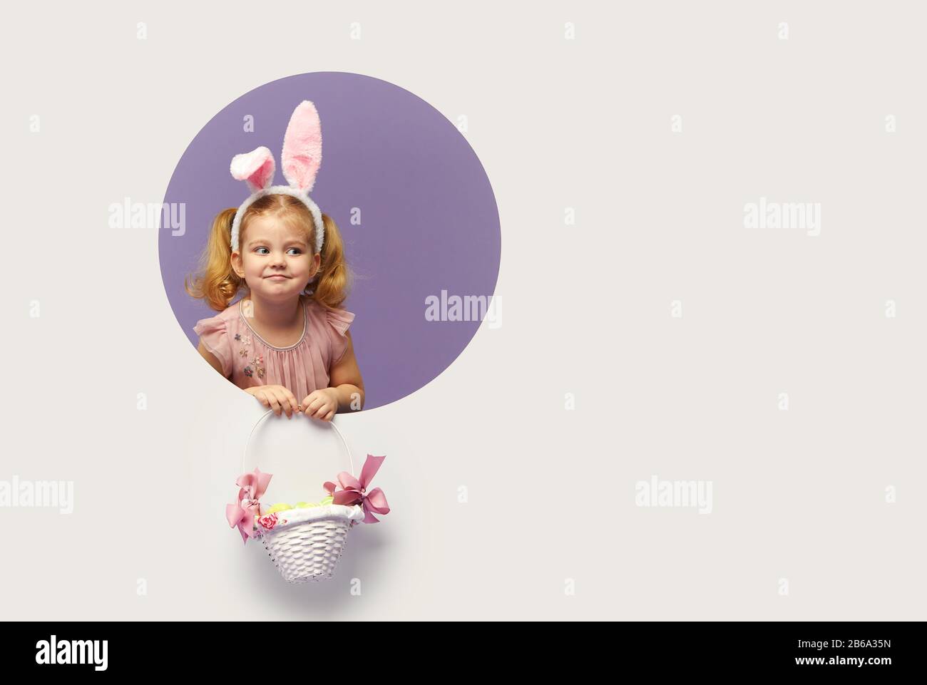 Easter card. Cute little child girl with bunny ears holding basket of ...