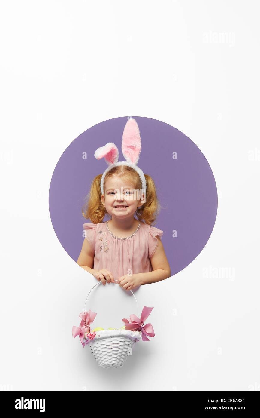Easter card. Cute little child girl with bunny ears holding basket of ...
