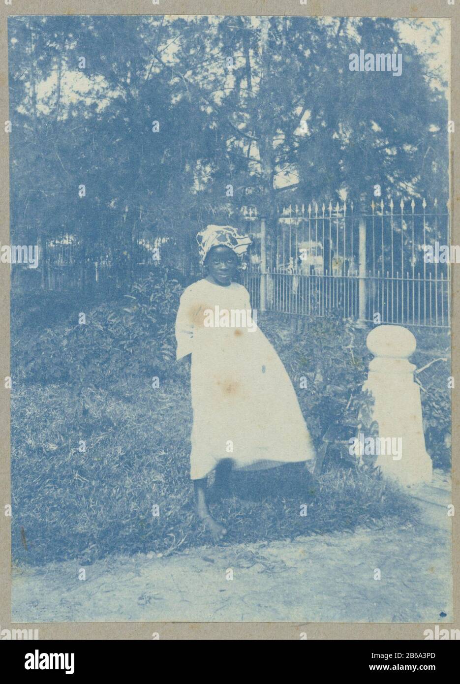 Girl standing at the entrance to the penny graveyard Where: apparently too Paramaribo. Part of the album Souvenir de Voyage (Part 2), about the life of the Doijer family in and around the plantation Ma Retraite in Suriname during the years 1906-1913. Manufacturer : Photographer: Hendrik Doijer (attributed to) Place manufacture: Suriname Date: 1906 - 1913 Physical features: cyanotypie Material: paper Technique: cyanotypie Dimensions: photo: h 110 mm × W 81 mm Date: 1906 - 1913 Stock Photo