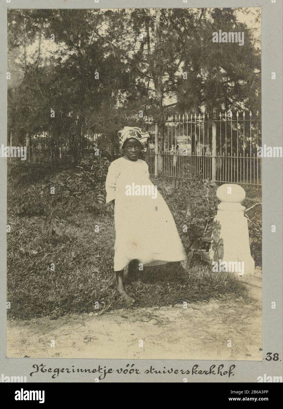 Girl standing at the entrance to the cemetery penny, Where: apparently Paramaribo. Part of the album Souvenir de Voyage (Part 2), about the life of the Doijer family in and around the plantation Ma Retraite in Suriname during the years 1906-1913. Manufacturer : Photographer: Hendrik Doijer (attributed to) Place manufacture: Suriname Date: 1906 - 1913 Physical features: gelatin silver print material: paper Technique: gelatin silver print dimensions: photo: h 111 mm × W 81 mm Date: 1906 - 1913 Stock Photo