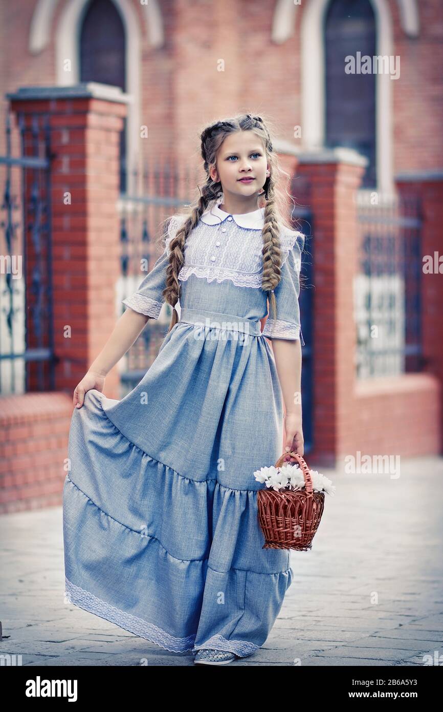 Beautiful girl in retro dress carries a basket with flowers Stock Photo