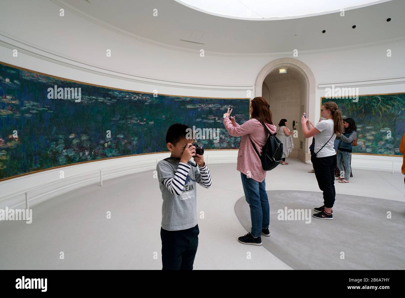 Visitors taking photos of Claude Monet's Les Nympheas Water Lilies series mural display in Musee de l'Orangerie.Paris.France Stock Photo