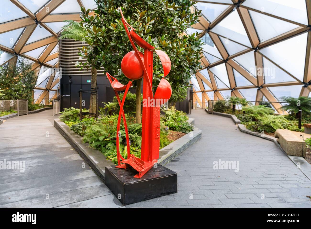 Shepherd of the Sun, red steel sculpture by Michael Lyons in context of Crossrail Place Roof Garden, Canary Wharf, London Stock Photo