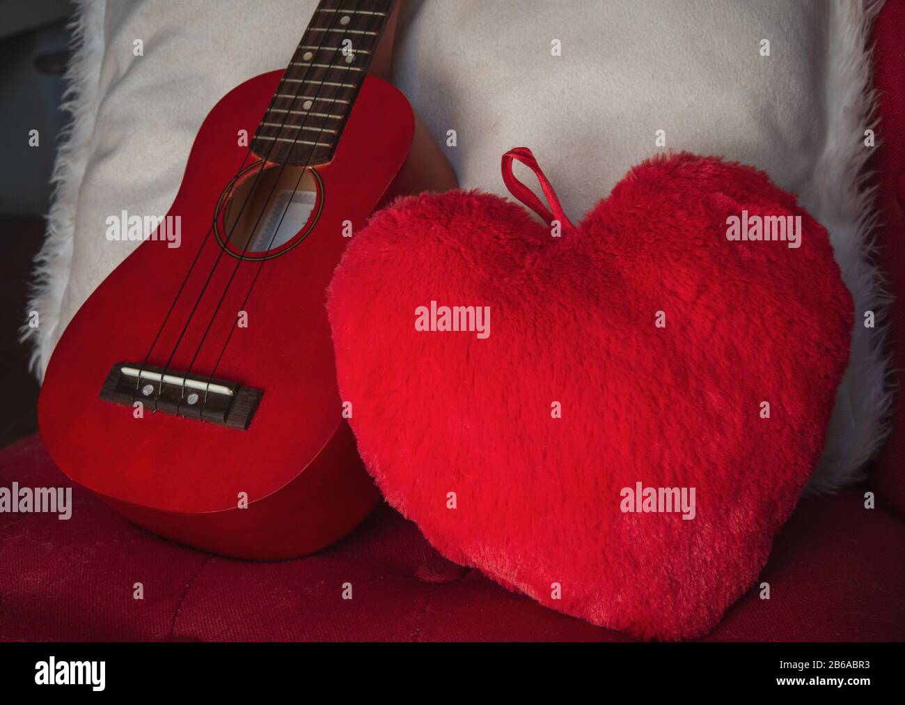 ukulele on chair with red heart cushion  concept I love music ,cosy warm weekend. Stock Photo
