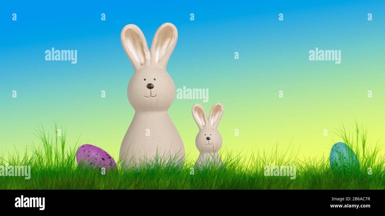 two easter bunnys stand on a meadow with easter eggs Stock Photo