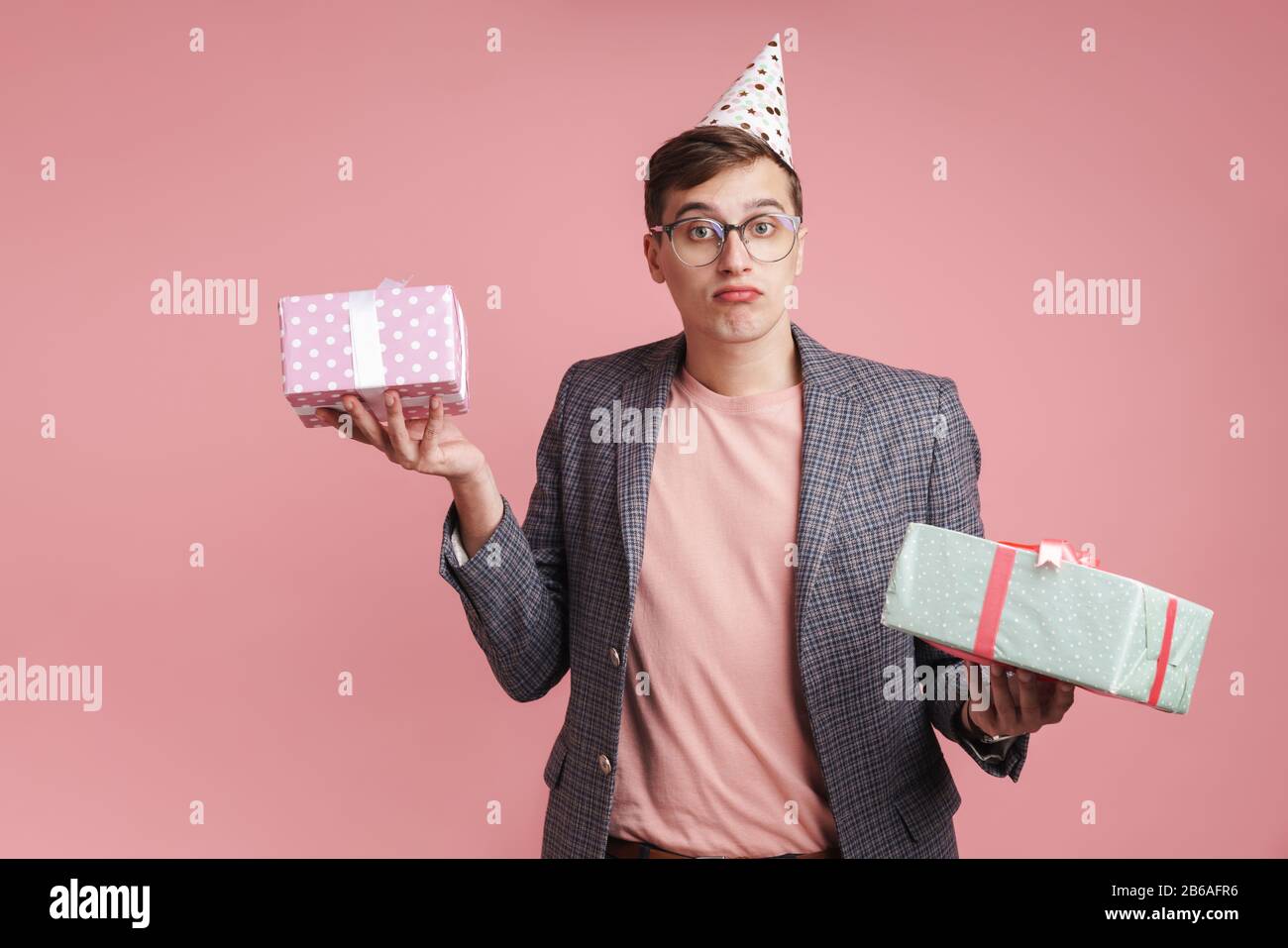 Image of a confused young guy in glasses holding birthday present gift ...