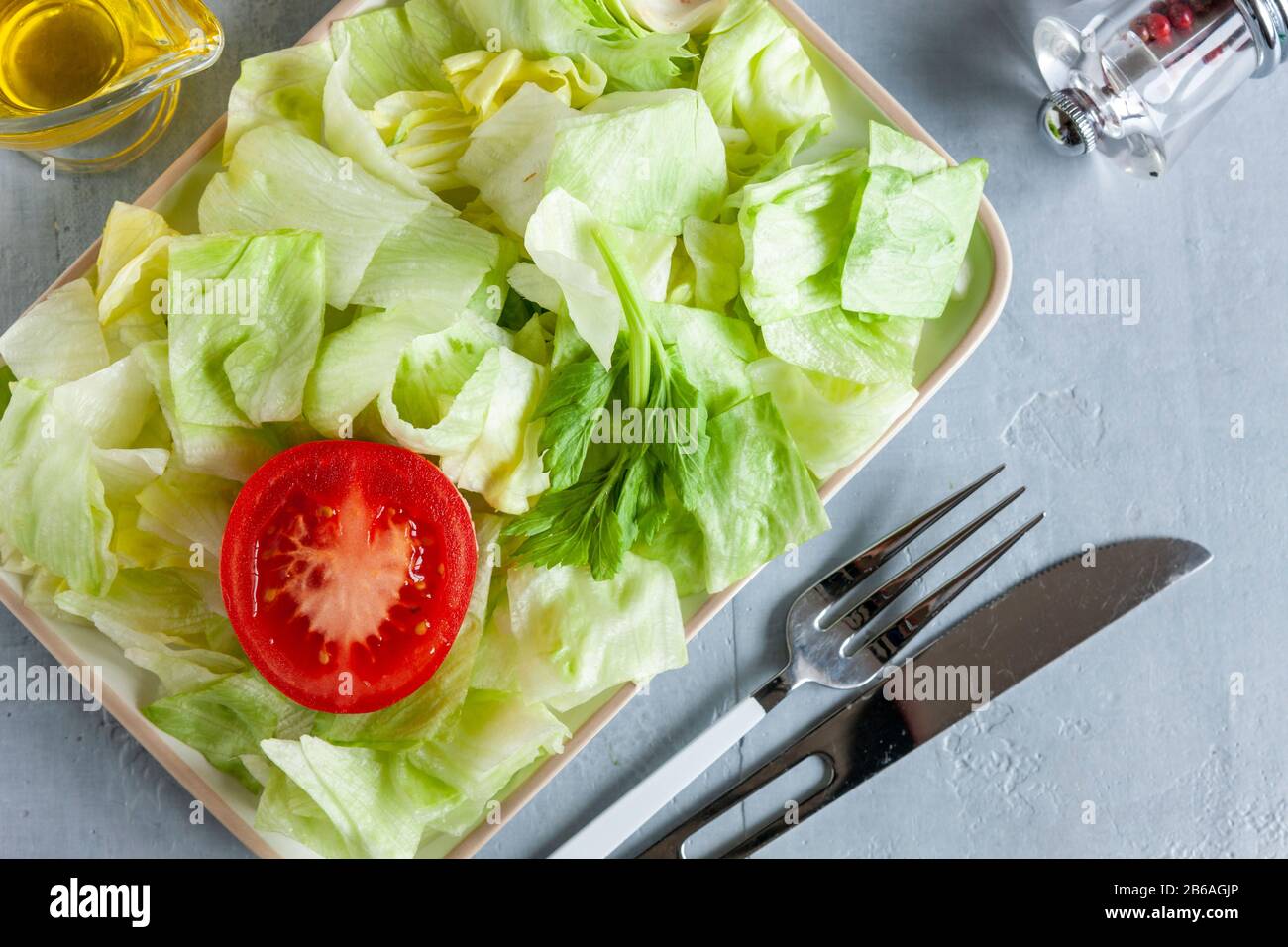 Plate with green iceberg lettuce, olive oil,tomatoe, Intermittent