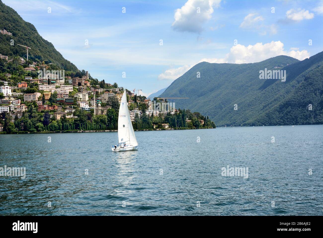 LUGANO, SWITZERLAND - JULY 5, 2014: Sailboat on Lake Lugano, with Mt. Bre and Castagnola in the background. The lake is a glacial lake situated on the Stock Photo