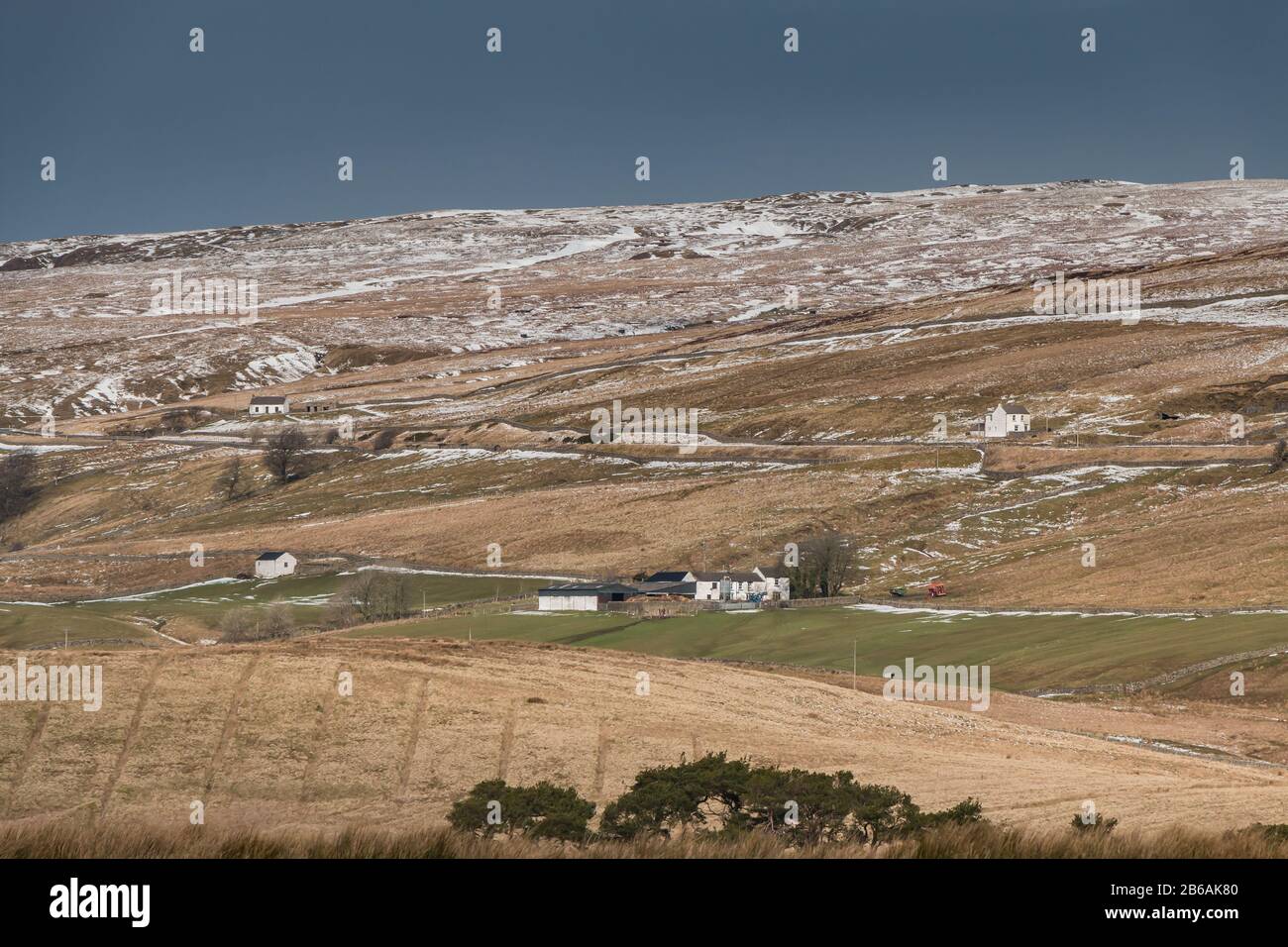Strong early spring sunshine and a dark sky create dramatic lighting on this wintry view of Harwood, Upper Teesdale Stock Photo