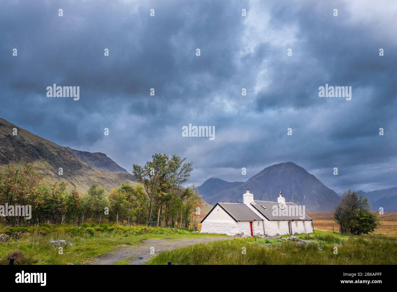 Blackrock Cottage under stormy skies with mountains in the background. Glencoe, Scottish Highlands, United Kingdom Stock Photo