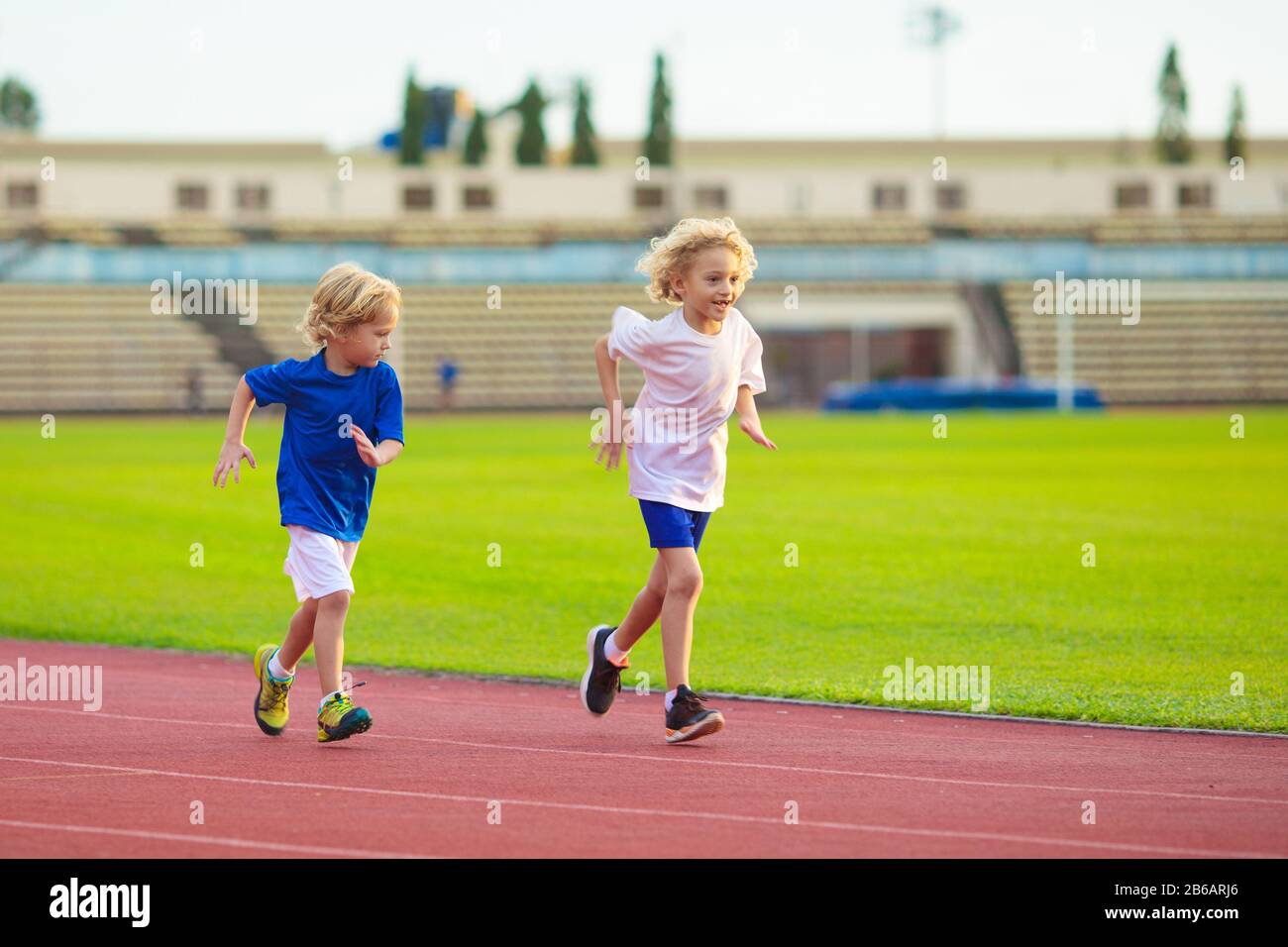 Child running in stadium. Kids run on outdoor track. Healthy sport