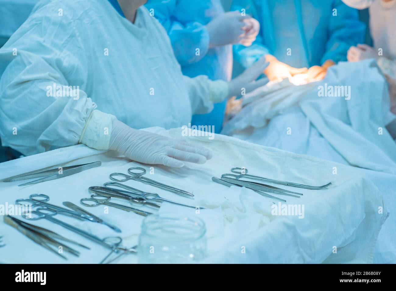 closeup, the hands of a nurses hand, an assistant surgeon takes a surgical instrument from a sterile table. In a sterile operating room. Removing a ma Stock Photo