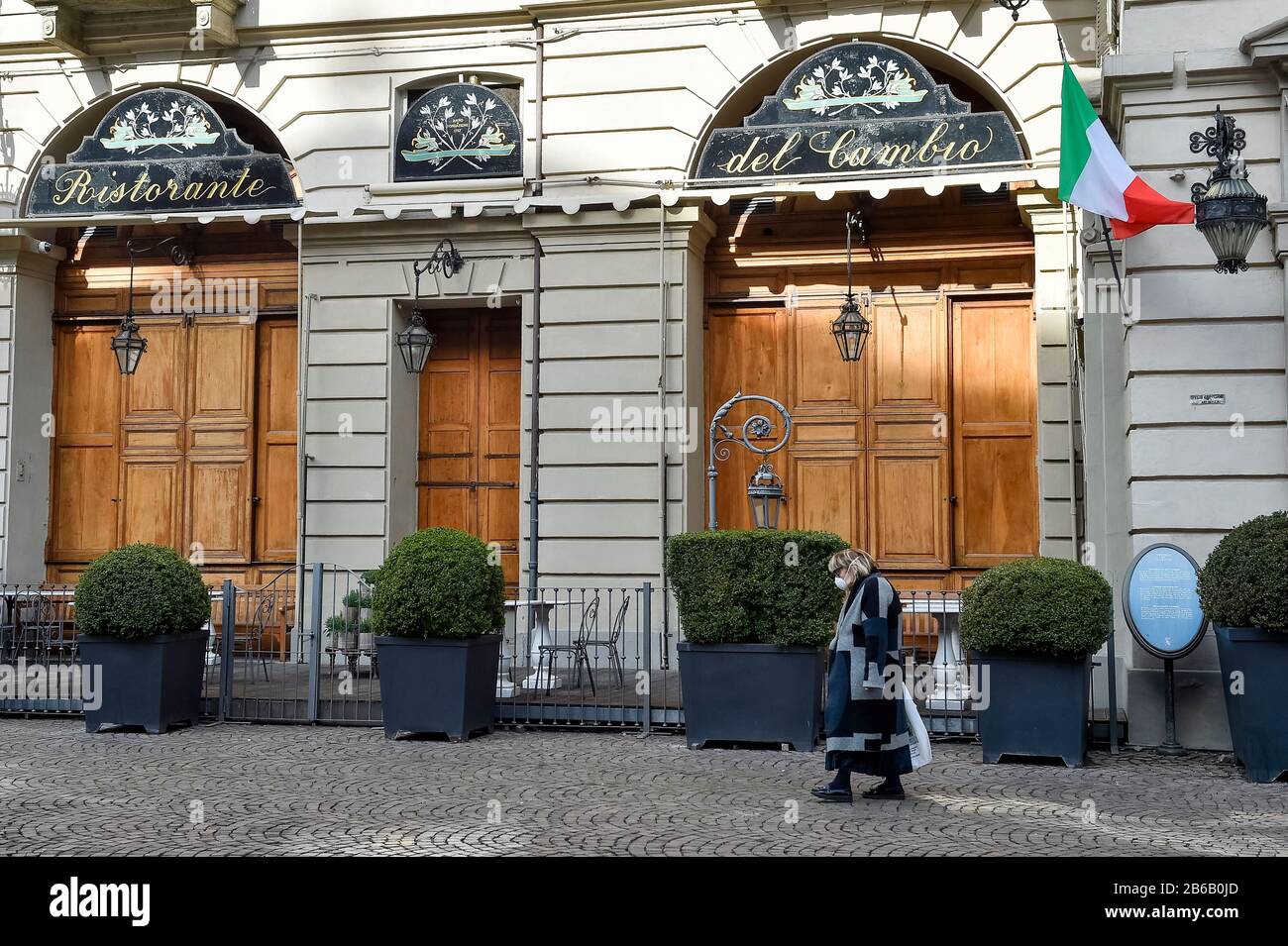 Turin, Italy. 10th Mar, 2020. TURIN, ITALY - March 10, 2020: A woman wearing a respiratory mask walks past closed Dal Cambio restaurant . The Italian government puts the whole country on lockdown as Italy is battling the world's second-most deadly COVID-19 coronavirus outbreak after China. (Photo by Nicolò Campo/Sipa USA) Credit: Sipa USA/Alamy Live News Stock Photo