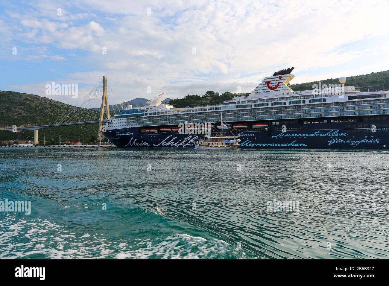 The TUI Cruises cruise ship Mein Schiff 2 moored up near the suspension bridge with an older sailing ship going past at Dubrovnik, Croatia Stock Photo