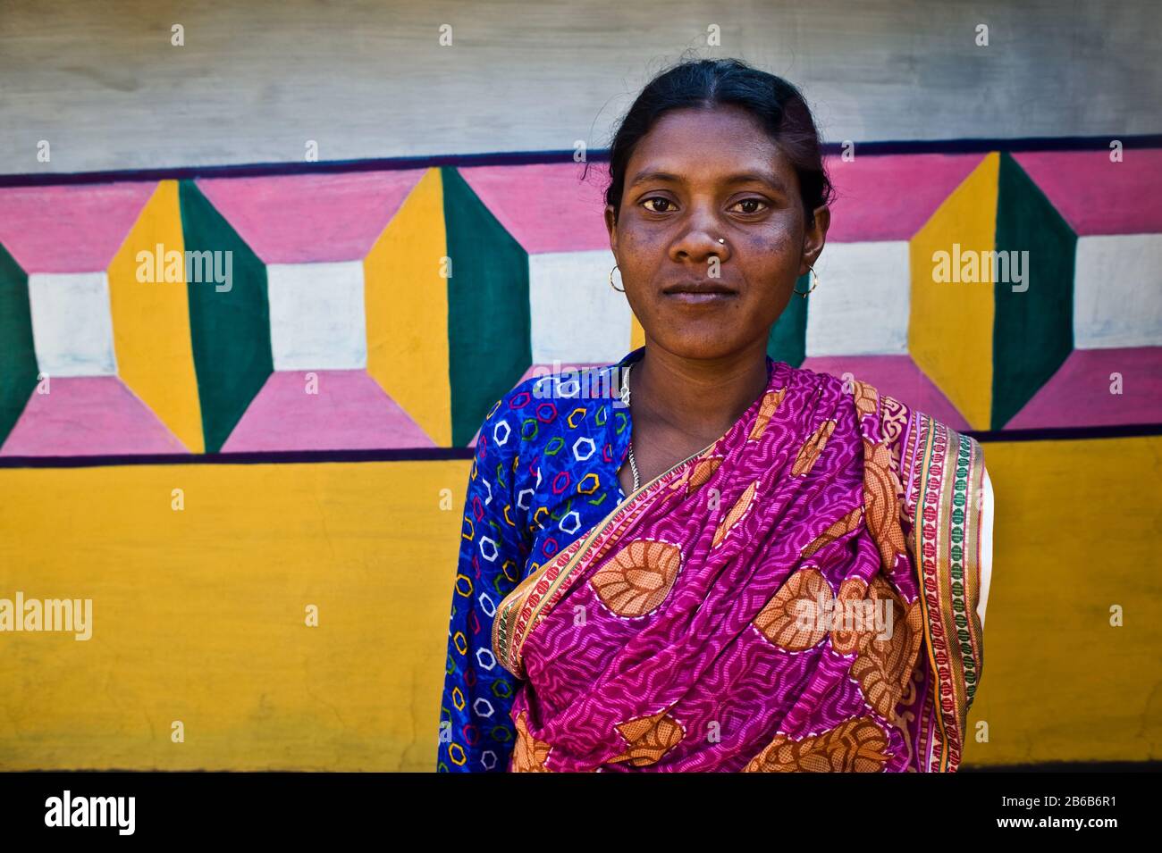 Tribal painter standing in front of the house she has painted ( India). She belongs to the Santhal tribe. Stock Photo