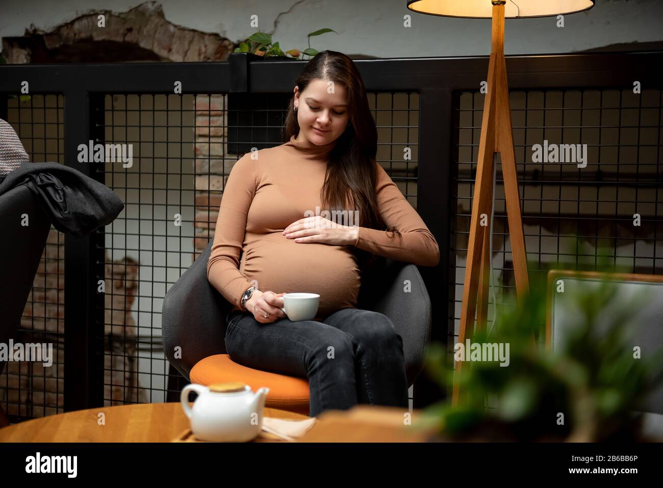 Pregnant woman sitting with cup of tea inside cafe Stock Photo - Alamy