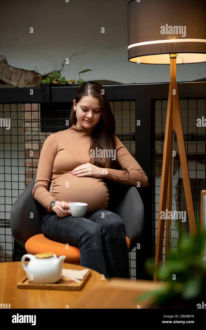 Pregnant woman sitting with cup of tea inside cafe Stock Photo - Alamy